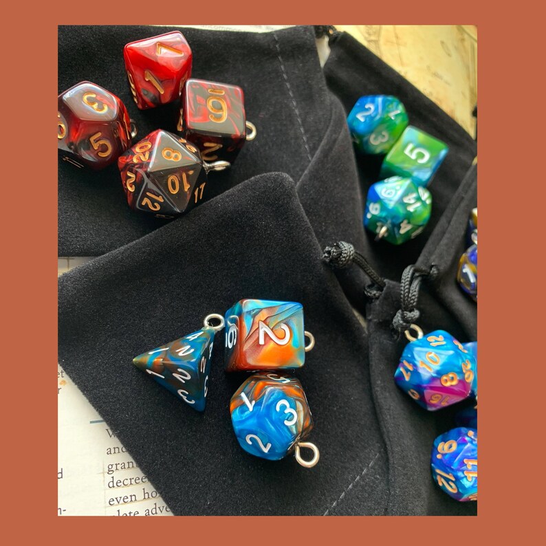 May include: A collection of colorful dice with gold accents, some are in a black velvet bag, others are scattered on a table. The dice are multi-sided and have different numbers on each side.