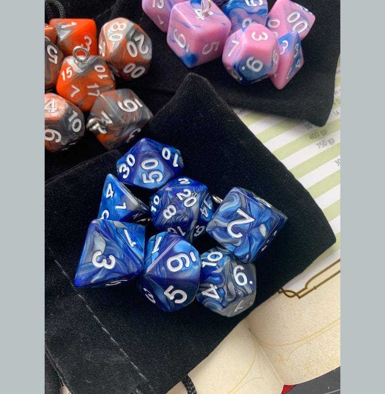 May include: A collection of blue and white marbled dice with white numbers. The dice are in a black velvet bag.