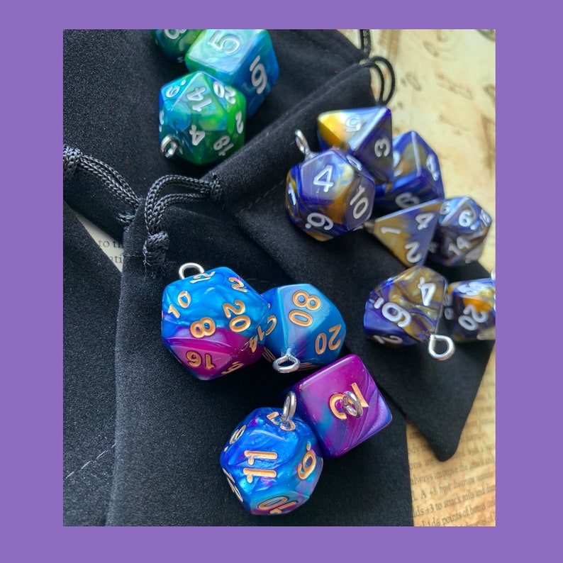 May include: A collection of iridescent dice with gold and silver accents. The dice are in a black velvet bag and are various shapes and sizes. The dice are blue, green, purple, and gold.