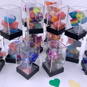 May include: A collection of 10 clear acrylic display boxes with black bases, each containing a set of colorful, multi-sided dice. The dice are made of various materials, including plastic and resin, and feature different colors and patterns.