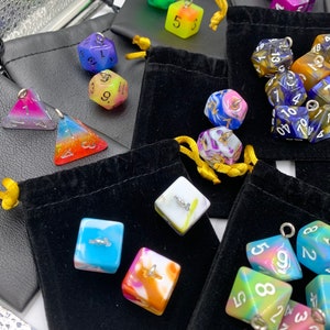 May include: Assortment of colorful dice with different numbers and patterns. The dice are made of resin and have a glossy finish. They are packaged in small velvet bags.