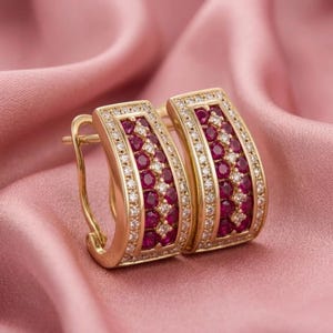 Puede incluir: Un par de pendientes de aro de oro con un diseño rectangular curvado. Cada pendiente está engastado con dos filas verticales de rubíes redondos de color rojo intenso, bordeados por dos filas de pequeños diamantes blancos, con cierre de bisagra.