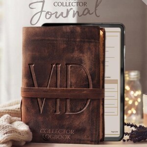 May include: A brown leather-look journal with the letters VID embossed on the front cover, featuring a horizontal strap closure. The text THE COLLECTOR JOURNAL and COLLECTOR LOGBOOK are printed on the cover. A tablet displays a digital page layout.