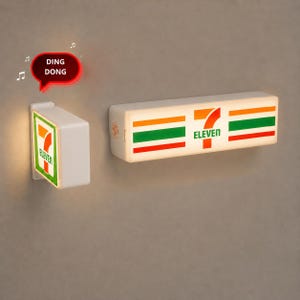 May include: Two white rectangular wall-mounted signs featuring the 7-Eleven logo with orange, green, and red horizontal stripes. One sign is square and the other is elongated. A red speech bubble graphic with the text DING DONG is visible.