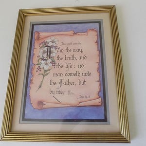 May include: Framed artwork featuring a scriptural quote from John 14:6, with the text "I am the way, the truth, and the life." The artwork is set against a parchment-style background, adorned with floral accents, and framed in a gold-colored frame.