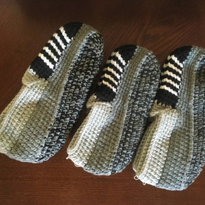 May include: Three pairs of gray and black crocheted slippers with white stripes.