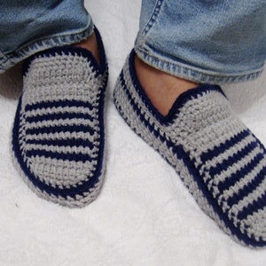 May include: A pair of gray and blue striped crocheted slippers. The slippers have a simple design and are made with a soft yarn.