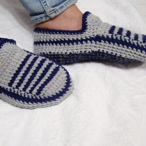 May include: A pair of gray and blue striped crocheted slippers. The slippers are made with a soft yarn and have a comfortable fit.
