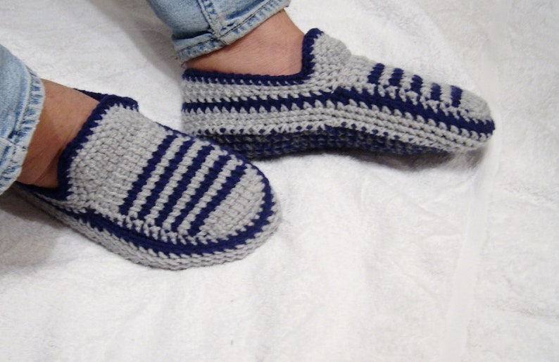 May include: A pair of gray and blue striped crocheted slippers. The slippers are made with a soft yarn and have a comfortable fit.
