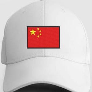 Op de afbeelding: Een witte honkbalpet met een rechthoekige geborduurde patch aan de voorzijde. De patch toont de nationale vlag van China, bestaande uit een effen rode achtergrond met één grote gele ster en vier kleinere gele sterren in een boogvorm.