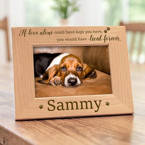 Op de afbeelding: Een lichtgekleurde houten fotolijst met de gegraveerde tekst "If love alone could have kept you here, you would have lived forever" aan de bovenkant en de naam "Sammy" aan de onderkant, voorzien van kleine pootafdrukjes aan beide zijden.
