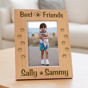 Vertical wood picture frame featuring laser-engraved paw prints along the sides. the text Best Friends with a heart icon on top panel, and the bottom border features the names.