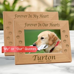 May include: Two light-colored wooden picture frames featuring engraved paw prints along the sides. The top frame reads Forever In My Heart, while the bottom frame reads Forever In Our Hearts, Turton, and 2010-2023, with a photo of a golden dog.