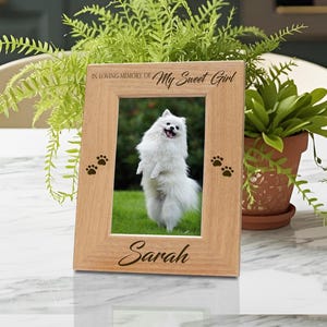 May include: A wooden picture frame with a photo of a white dog standing on its hind legs. The frame has the text "IN LOVING MEMORY OF My Sweet Girl" and "Sarah". Paw prints are on the frame.