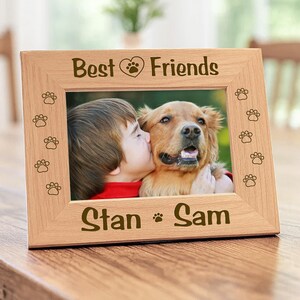 Wood picture frame featuring laser-engraved paw prints along the sides. Engraved text Best Friends with a heart icon on top panel, and the bottom border features the names.