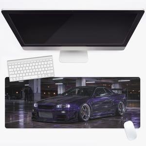 Puede incluir: Una alfombrilla de escritorio rectangular con una impresión de alta resolución de un Nissan Skyline GT-R morado modificado, estacionado en un garaje de hormigón con poca luz. El coche tiene un kit de carrocería ancho, ruedas metálicas y un intercooler.