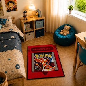 May include: A rectangular area rug featuring a red Nintendo Game Boy cartridge design with a central graphic of the Pokémon Red video game cover, including the text Nintendo GAME BOY, Pokémon, and an E rating symbol on a dark floor.