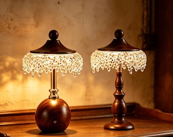May include: Two table lamps featuring dark wood bases and matching wood-topped shades with clear, hanging crystal-like teardrop accents. The left lamp has a spherical base, while the right lamp has a turned pedestal base, both emitting warm light.