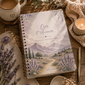 Könnte beinhalten: Ein spiralgebundenes Notizbuch mit einer Aquarellillustration eines Lavendelfeldes, eines gewundenen Pfades und Bergen. Das Cover zeigt den Text Oser et Avancer, Carner pour créer son prochain chapitre und Ame Libre mit einem kleinen Herz.