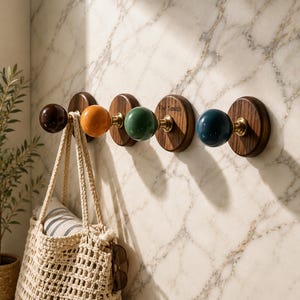 May include: A wall-mounted coat rack featuring four circular dark wood bases with brass hardware and colorful spherical knobs in brown, orange, green, and blue. The third wooden base is engraved with the text The Smith in black lettering.