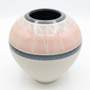May include: A spherical ceramic vase featuring a wide opening with a dark grey rim. The upper portion is glazed in a soft pink with white etched triangular patterns and small blue dots. A dark grey horizontal band separates the pink top from the cream-coloured base.