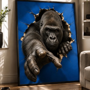 Pode incluir: Uma impressão de arte emoldurada apresentando um gorila cinza-escuro realista emergindo através de um buraco rasgado em um fundo azul vibrante. O gorila é retratado com a cabeça e os braços para frente, com uma mão estendida em direção ao observador.