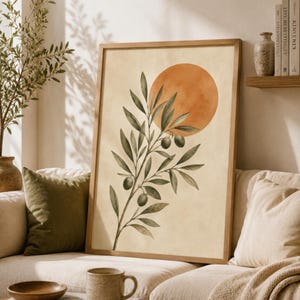 May include: A framed wall art print featuring a watercolour illustration of an olive branch with green leaves and dark olives set against a cream background with a large, solid orange circle positioned behind the upper portion of the branch.