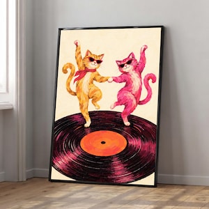 Puede incluir: Una lámina de arte enmarcada que muestra a un gato naranja y a un gato rosa con gafas de sol negras bailando sobre un gran disco de vinilo negro con una etiqueta central naranja. Los gatos se dan la pata y el gato naranja lleva un pañuelo rojo al cuello.