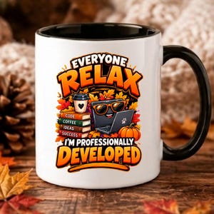 Könnte beinhalten: Ein weißer Keramikbecher mit schwarzem Henkel und Innenseite, bedruckt mit einem Laptop mit Sonnenbrille, einem Bücherstapel mit der Aufschrift Code, Coffee, Ideas, Success und einem Kürbis, sowie dem Text Everyone Relax I'm Professionally Developed.