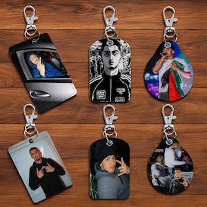 May include: A collection of six custom keychains featuring various photographic and illustrated portraits of a young man. Each keychain includes a silver-toned metal lobster clasp and ring, displaying distinct images of the same individual in different settings and outfits.