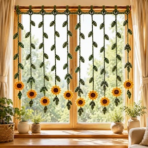 May include: A crochet window valance featuring a horizontal green vine pattern with multiple vertical hanging strands. Each strand is adorned with small green leaves and a single bright yellow sunflower at the bottom, suspended from a wooden rod.