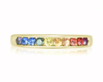 May include: A gold band ring with a rainbow of sapphires set in a row. The sapphires are in the order of a rainbow, from violet to red.