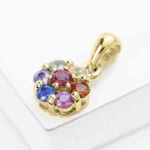 May include: A gold pendant featuring a cluster of colourful gemstones, including red, blue, green, orange, and purple.