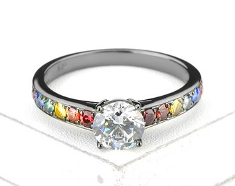 May include: A black band ring with a large, clear center stone and a rainbow of smaller stones set around the band.