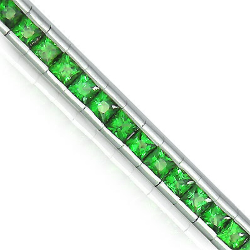 Puede incluir: Una pulsera de plata con una fila de piedras preciosas cuadradas de color verde esmeralda.