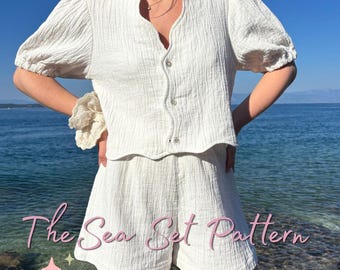 May include: A white two-piece set consisting of a short-sleeved button-down top with a textured fabric and matching shorts. The text "The Sea Set Pattern" is visible in pink script, along with "LUCKY LINE" and small star icons.