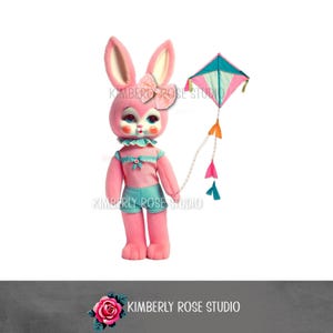 May include: A pink bunny doll with a bow, wearing a pink top and teal shorts, holding a kite. The kite is pink, teal, and white with colorful streamers. The doll has large eyes and a ruffled collar. The image includes the text "KIMBERLY ROSE STUDIO".