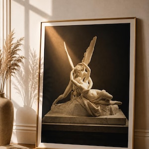 Può includere: Una stampa artistica incorniciata con una fotografia monocromatica della scultura in marmo Psiche rianimata dal bacio dell'amore. L'immagine mostra una figura alata china su una figura distesa, su sfondo scuro con cornice dorata.