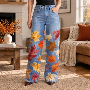 Op de afbeelding: Lichtblauwe jeans met hoge taille, wijde pijpen en een all-over print van herfstbladeren in tinten geel, oranje en donkerrood. De broek is voorzien van een klassieke sluiting met knoop en ritssluiting en heeft vijf zakken.