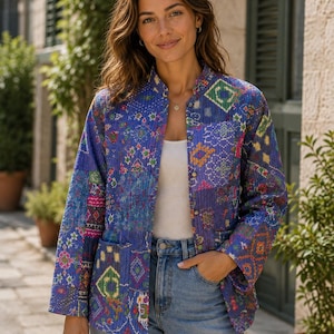 May include: A long-sleeve quilted jacket featuring a vibrant patchwork pattern in shades of blue, purple, orange, and green. The jacket has a mandarin collar, a front button closure with metallic buttons, and two square patch pockets on the front.