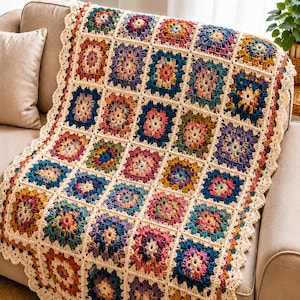 May include: A handmade crochet blanket featuring a repeating granny square pattern in various colors including deep blue, mustard yellow, pink, and purple, all joined by a cream-colored yarn border with a decorative scalloped edge finish.