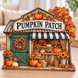 Può includere: Un'insegna decorativa in legno a forma di bancarella con la scritta PUMPKIN PATCH. Presenta una porta verde con una ghirlanda di girasoli, una tenda a righe blu e bianche, scaffali pieni di varie zucche e fogliame autunnale.