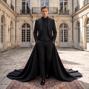 May include: A black three-piece suit featuring a tailored jacket, a matching vest, and slim-fit trousers. The jacket includes an attached long, flowing train that extends behind the garment, creating a dramatic silhouette on the floor.