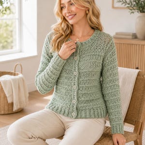 Op de afbeelding: Een saliegroen vest met lange mouwen, voorzien van een gehaakt patroon met textuur, een ronde halslijn en een knoopsluiting aan de voorzijde met vijf bijpassende ronde knopen. Het kledingstuk heeft een getailleerd model met geribbelde boorden.