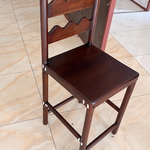 May include: A dark brown wooden bar stool featuring a square seat and a backrest with two horizontal slats, each designed with a scalloped top edge. The stool has four straight legs connected by horizontal support bars on all four sides.
