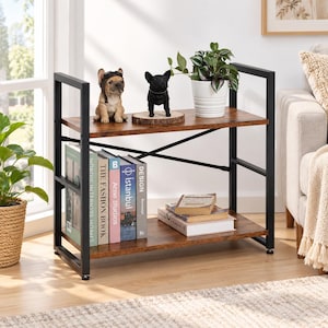 May include: A two-tier bookshelf with a dark brown wood-grain finish and a black metal frame. The top shelf holds two French bulldog figurines and a potted plant in a white ribbed pot. The bottom shelf contains several books stacked vertically.