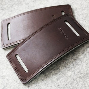 May include: Two brown leather patches with stitched edges. The top patch has the word "KNOX" embossed on it. The bottom patch has the word "CLEMSON" embossed on it.