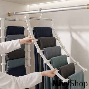 Puede incluir: Un colgador de pantalones de varios niveles hecho de metal blanco y plateado con múltiples varillas horizontales para organizar pantalones. El soporte cuelga de una barra y sostiene varios pantalones doblados en tonos azul marino y gris.