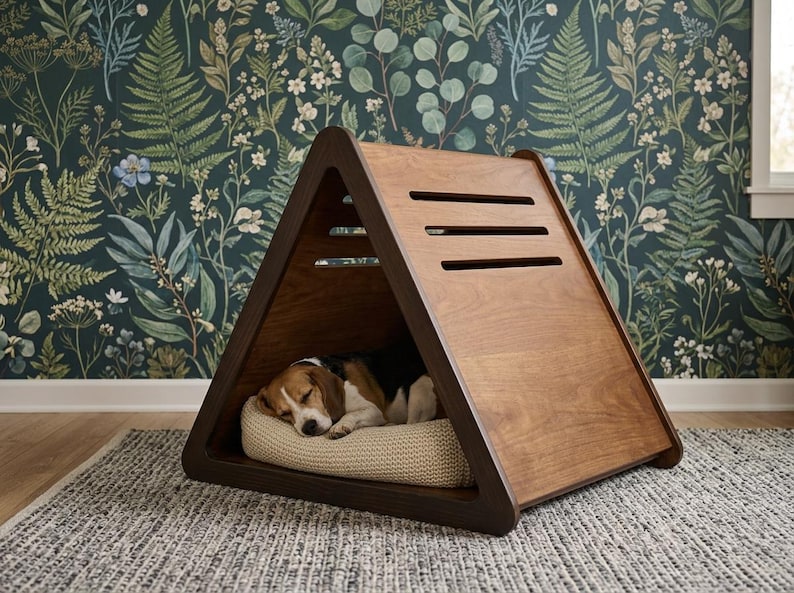 May include: A triangular wooden pet house with a smooth brown finish and three horizontal ventilation slats on the side. Inside the structure, a beagle dog with brown, black, and white fur is sleeping on a textured beige rectangular cushion.