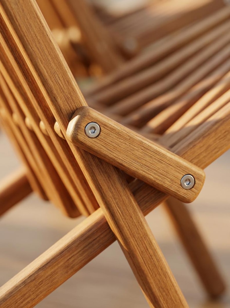 May include: A folding chair constructed from light brown wood with a slatted seat and backrest. The frame features visible metal bolts at the joints, connecting the legs and armrests in a cross-brace design with a natural wood grain finish.